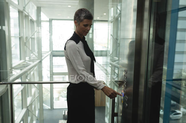 Geschäftsfrau drückt im Büroaufzug einen Knopf — Stockfoto