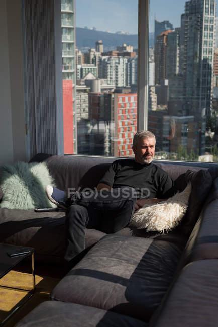 Nachdenklicher Mann entspannt sich im heimischen Wohnzimmer — Stockfoto