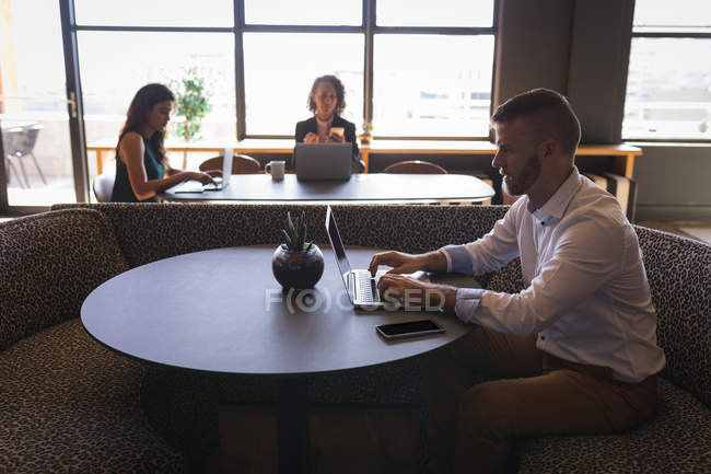 Керівники бізнесу сидять і працюють на ноутбуці в кафетерії в офісі — стокове фото