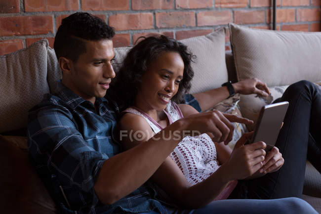 Couple utilisant une tablette numérique dans le salon à la maison — Photo de stock