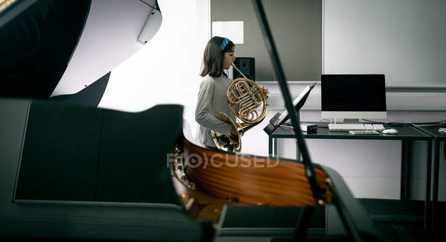 Adorabile studentessa che suona il corno francese nella scuola di musica — Foto stock