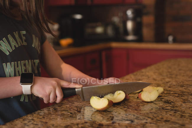 Menina maçã de corte na cozinha em casa — Fotografia de Stock