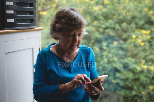 Seniorin benutzt Handy zu Hause — Stockfoto