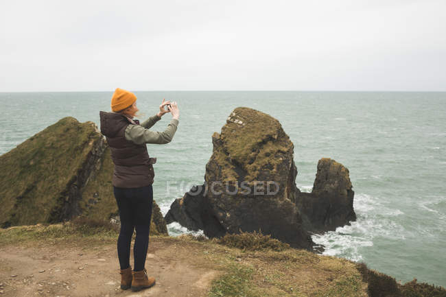 Молода жінка-пішохідка фотографує море — стокове фото