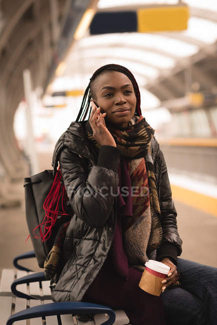 Giovane donna che parla al cellulare alla stazione ferroviaria — Foto stock