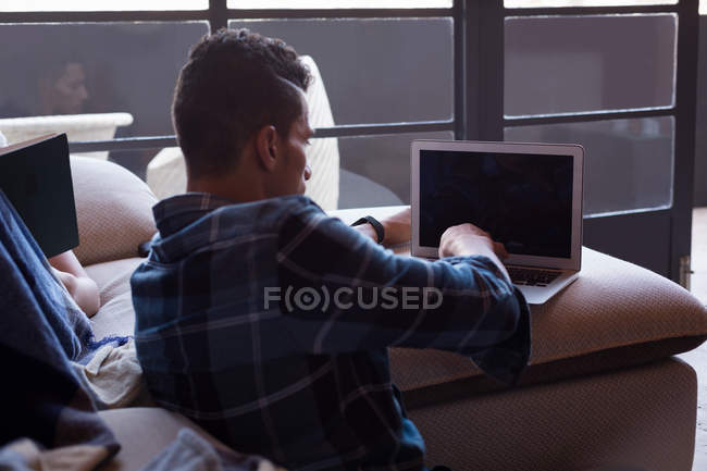 Человек, использующий ноутбук в гостиной дома — стоковое фото