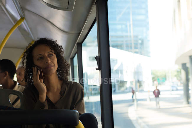 Женщина разговаривает по мобильному телефону во время поездки в автобусе — стоковое фото