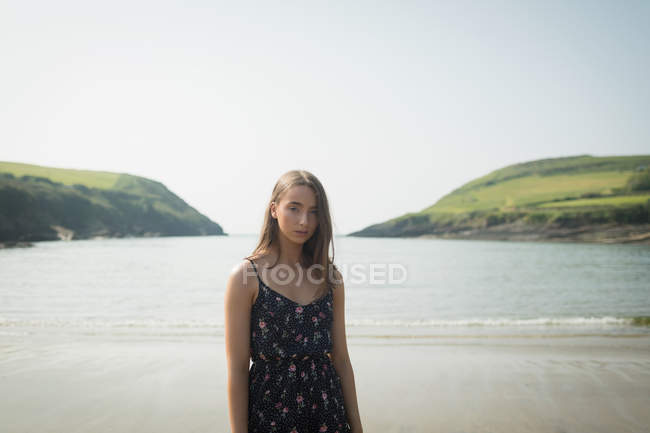 Schöne Frau, die am Strand steht und in die Kamera schaut — Stockfoto