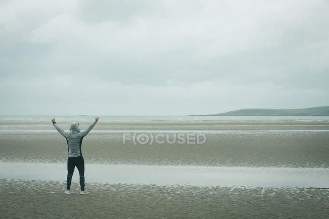 Вид сзади на счастливого человека, стоящего на пляже — стоковое фото