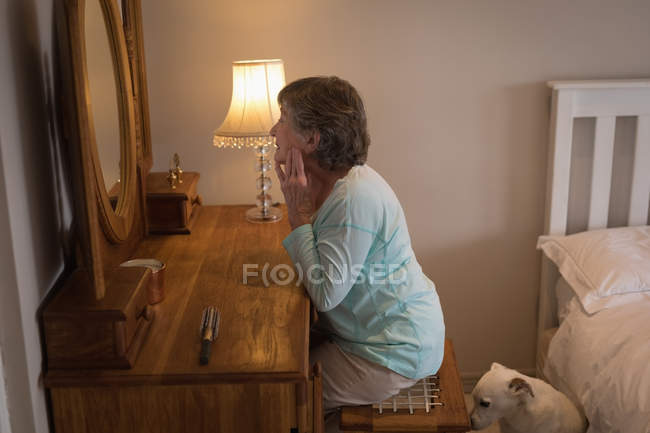 Старшая женщина смотрит на себя в зеркало в спальне — стоковое фото