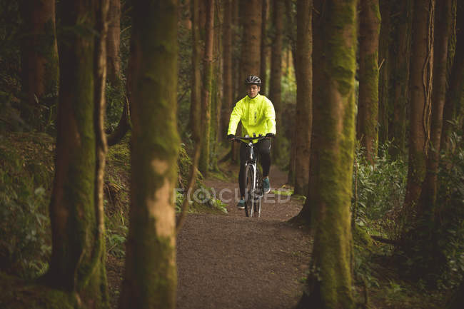 Молодий чоловік їде на велосипеді в лісі — стокове фото