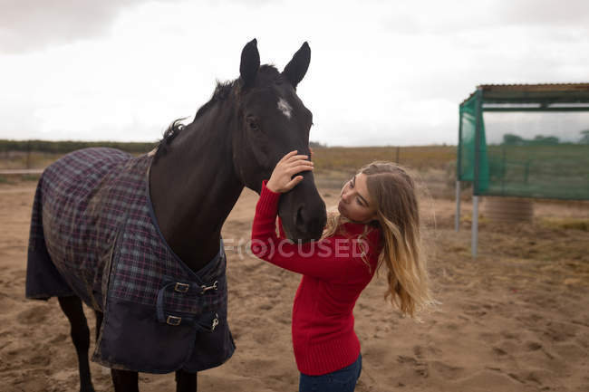 Adolescente acariciando un caballo en el rancho - foto de stock