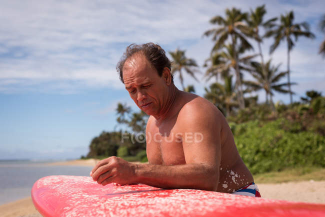Male surfer holding surfboard at beach — Stock Photo