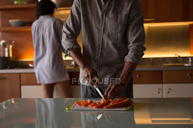 Homme coupe végétate dans la cuisine une maison — Photo de stock