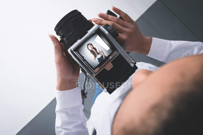 Жіночий фотограф, який натискає фотографії моделі в фотостудії — стокове фото