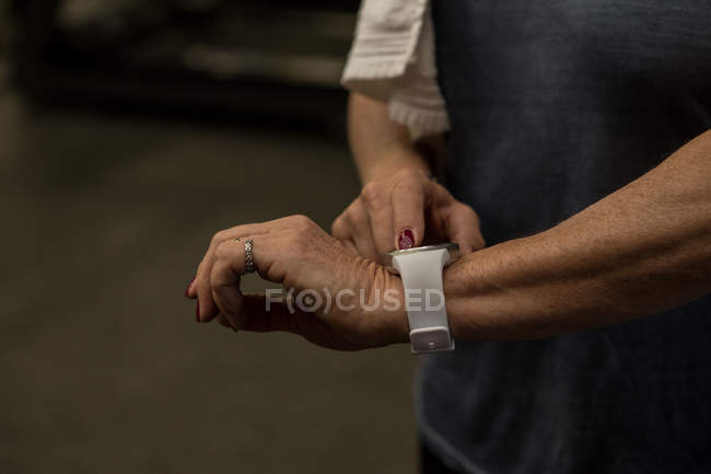 Partie médiane de la femme utilisant smartwatch dans la salle de gym — Photo de stock