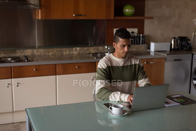 Чоловік використовує ноутбук на обідньому столі вдома — стокове фото