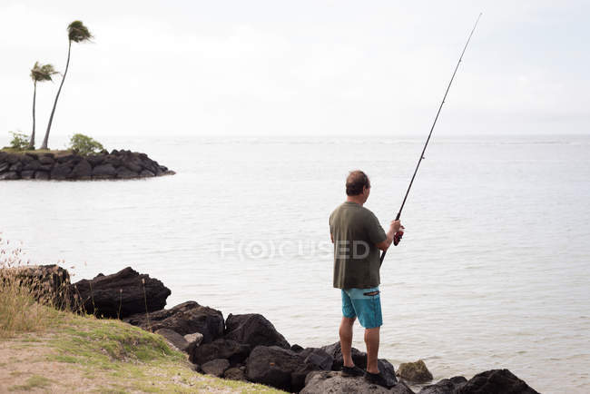 Vue arrière d'un pêcheur pêchant sur une plage — Photo de stock