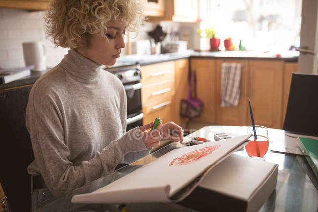 Jovem mulher colorir um esboço em casa — Fotografia de Stock