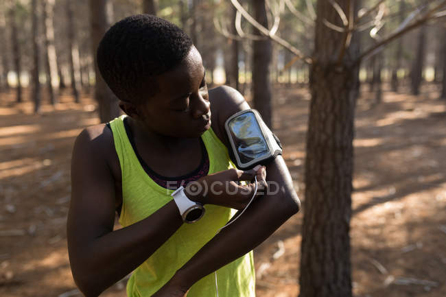 Atleta ascoltare musica da lettore mp3 smartphone nella foresta — Foto stock