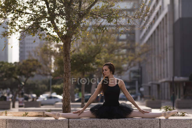 Танцовщица балета, растянувшаяся перед танцами на городской улице — стоковое фото