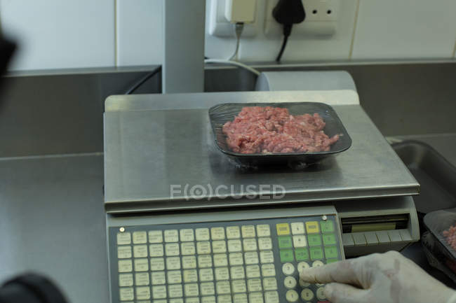 Macellaio che controlla il peso delle carni imballate in macelleria — Foto stock