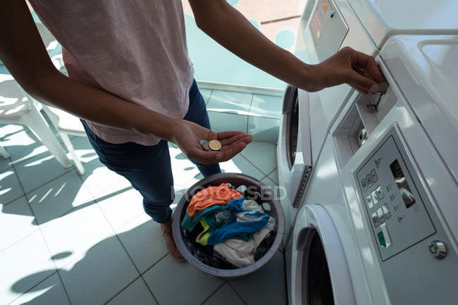 Frau steckt Münze in Waschsalon im Waschhaus — Stockfoto
