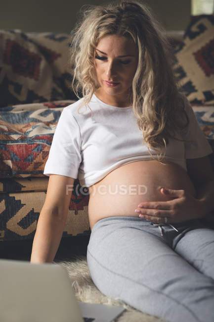 Pregnant woman touching her belly in living room at home — Stock Photo