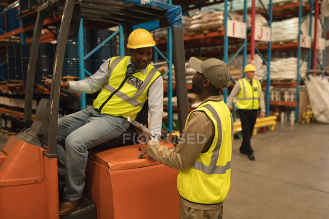 Trabalhadores do sexo masculino interagindo uns com os outros no armazém — Fotografia de Stock