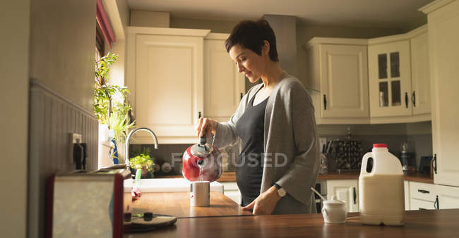Pregnant woman preparing coffee in the kitchen at home — Stock Photo