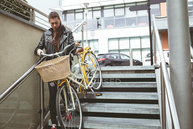 Beautiful woman with bicycle climbing down the stairs — Stock Photo