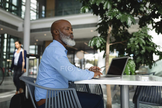 Pensativo hombre de negocios utilizando el ordenador portátil en la cafetería de la oficina - foto de stock