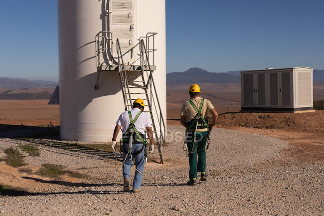 Engineers walking toward a wind mill at a wind farm — Stock Photo