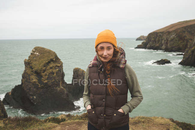 Retrato de una hermosa excursionista de pie contra el mar - foto de stock