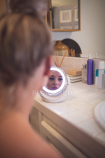 Schöne Frau blickt im Spiegel auf Badezimmer — Stockfoto