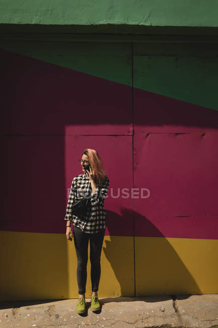 Young woman talking on mobile phone standing at pavement — Stock Photo