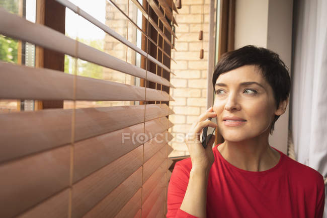 Жінка розмовляє по мобільному телефону у вітальні вдома — стокове фото