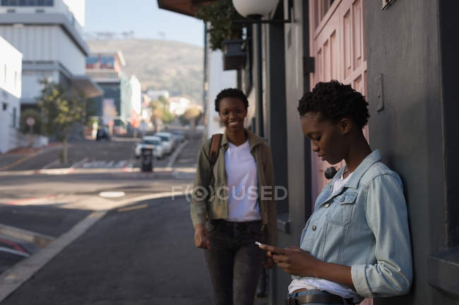 Близнецы используют мобильный телефон на городской улице в солнечный день — стоковое фото