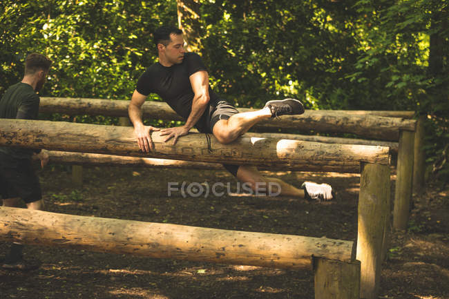 Entrenamiento de hombre en forma en el sendero de fitness en el campamento de entrenamiento - foto de stock