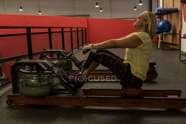 Donna disabile che si allena su una macchina in palestra — Foto stock