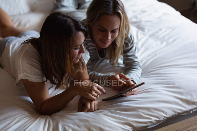 Lésbicas casal usando tablet digital no quarto em casa — Fotografia de Stock