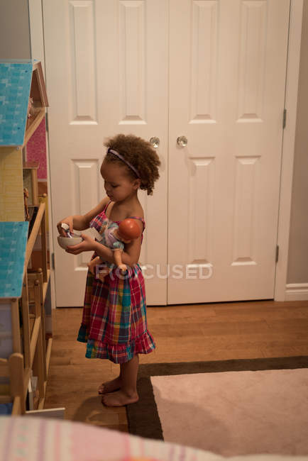 Стоящая девочка играет с игрушками дома — стоковое фото