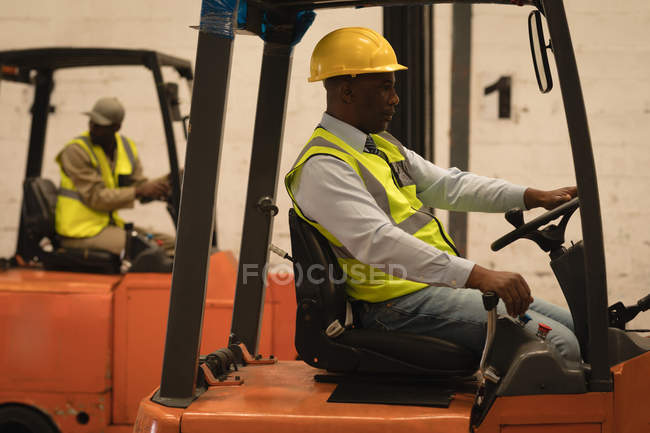 Masculino trabalhador condução empilhadeira no armazém — Fotografia de Stock