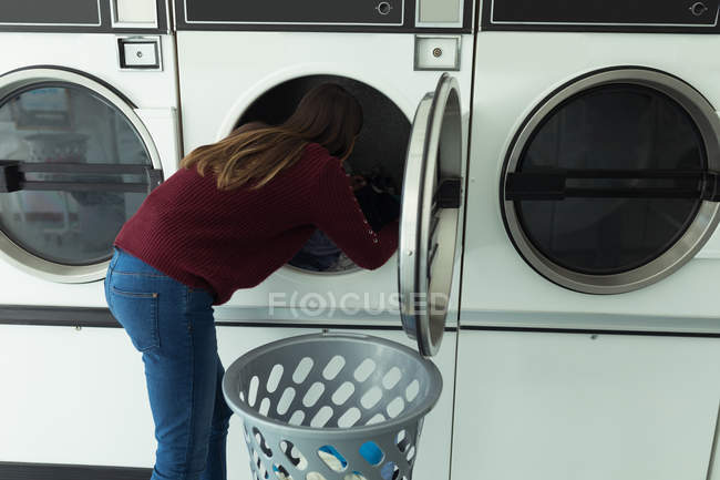 Jeune femme faisant la lessive dans la laverie automatique — Photo de stock