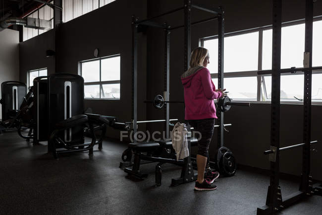 Зріла жінка з обмеженими можливостями використовує мобільний телефон у спортзалі — стокове фото