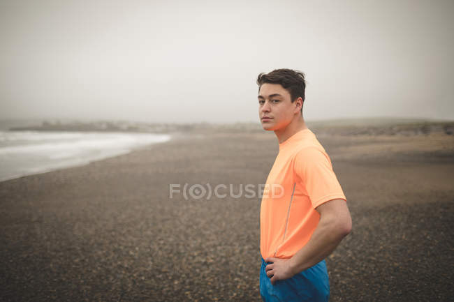 Jovem de pé na costa no mar — Fotografia de Stock