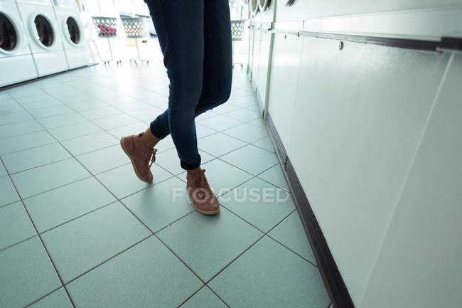 Legs of woman waiting at laundromat — Stock Photo