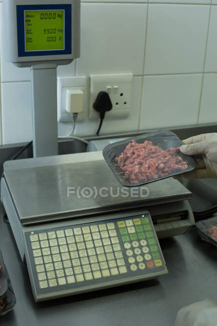 Butcher checking weight of packed meat — Stock Photo