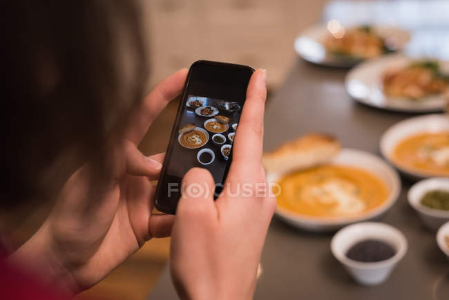 Woman clicking photo of food in kitchen at home — Stock Photo