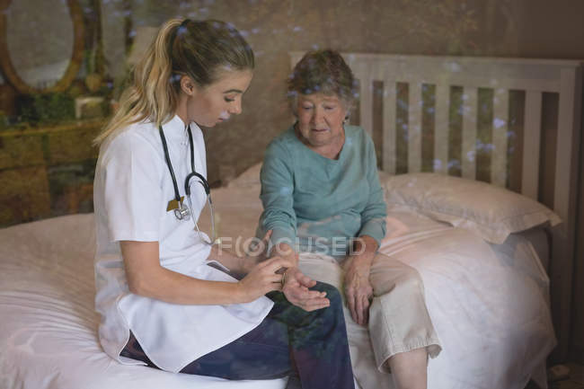 Fisioterapista che esamina una donna anziana a casa — Foto stock